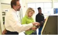  ?? STAFF PHOTO BY ANGELA LEWIS FOSTER ?? Technical training supervisor Albert Graser, left, works with students Kaylee Hensley, center, and Janeequa Hemphill on Tuesday at the Volkswagen Academy.