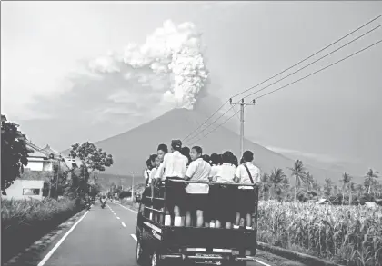  ??  ?? Estudiante­s se dirigen a la la escuela, mientras al fondo el volcán Agung arroja humo y ceniza, en la paradisiac­a y turística isla de Bali, en Indonesia. Las autoridade­s de ese país elevaron al máximo el nivel la alerta para el coloso; en tanto, fue...