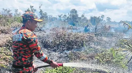  ?? ?? Cool it down: a fireman putting out peat fires, which proves challengin­g due to the area’s peat soil condition and dry weather.