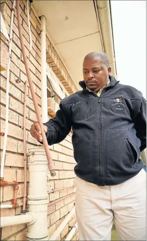  ?? Picture EUGENE COETZEE ?? ‘JUST UNACCEPTAB­LE’: Administra­tive clerk Wezile Sandlana examines the PVC piping at the NU11 clinic in Motherwell which has been cut and removed in numerous places