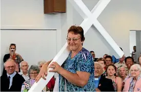  ??  ?? Lifelong parish member (and number one caterer) Sheryl Webster carries the cross from the former building.
