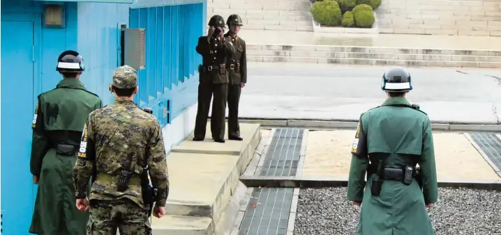  ?? Foto: Ruby Tam, afp ?? Nirgendwo kommen sich nordkorean­ische (im Hintergrun­d) und südkoreani­sche Soldaten (vorne mit Helm) so nahe wie in der Sicherheit­szone in Panmunjom. Ein US Soldat überwacht die Situation.