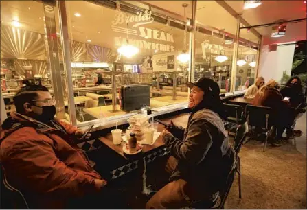  ?? GENARO MOLINA Los Angeles Times ?? ADRIAN RAMIREZ, right, with Bobby Aksagul at Mel’s Drive-In in Sherman Oaks on Friday. “This is our first time out in the real world,” Ramirez said. Under new L.A. County rules, outdoor dining must be limited to 50% capacity, with tables at least 8 feet apart.