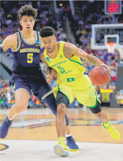  ?? | GETTY IMAGES ?? Oregon’s Tyler Dorsey drives around Michigan’s D. J. Wilson on Thursday at the Midwest Regional in Kansas City, Mo.