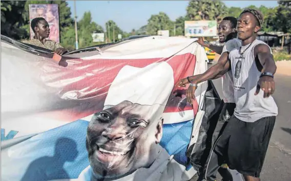  ?? Photo: Marco Longari/AFP ?? Face-off: Supporters of president-elect Adama Barrow tear down a banner of the incumbent Yahya Jammeh.