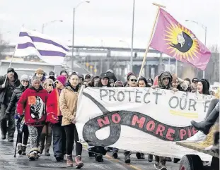 ?? ALLEN MCINNIS/MONTREAL GAZETTE ?? First Nations people from Kahnawake walked to Highway 132 as the moved their blockade from the CP Rail tracks to a green space next to the Mercier Bridge on Thursday.