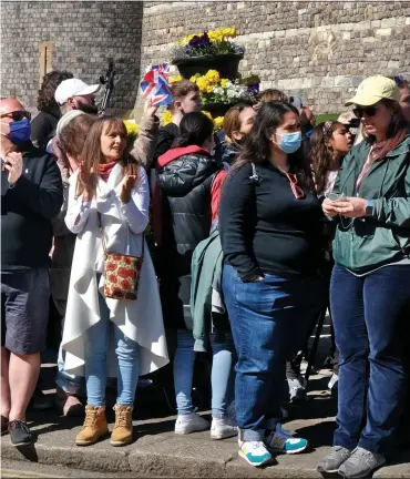  ??  ?? ‘WE JUST COULDN’T STAY AWAY’: Crowds line the streets around Windsor Castle, left; two women style their own tribute at Wellington Arch in London, above; Michaela Gregory, right, and her daughters Esmae, left, and Bella Rose