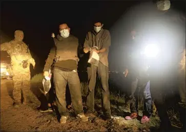  ?? Photograph­s by Gary Coronado Los Angeles Times ?? BORDER Patrol agents stop a group of migrants in McAllen, Texas. Though the agency’s main mission is apprehendi­ng those who cross illegally, it has begun more work to try to rescue and recover missing migrants.