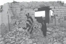  ?? ABDUL KHALIQ/AP ?? Afghan boys walk Saturday near a damaged house after airstrikes two weeks ago during a fight between government forces and the Taliban in Lashkar Gah, Helmand province, southweste­rn Afghanista­n.