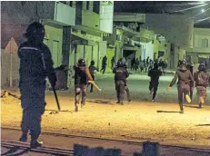  ?? AMINE LANDOULSI/THE ASSOCIATED PRESS ?? Riot police clash with demonstrat­ors during anti-government protests in Tebourba, south of Tunis, Tunisia, on Wednesday night.