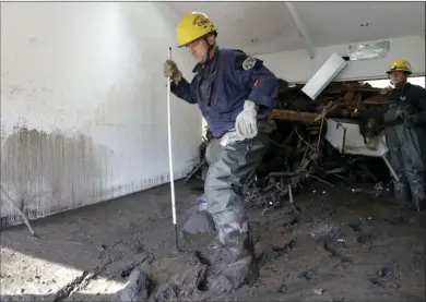  ?? PHOTO/MARCIO JOSE SANCHEZ ?? Richard Strange (left), of the Vandenberg Fire Department Search and Rescue, search an area damaged by storms in Montecito on Friday. AP