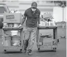  ??  ?? Jose Castillo pulls two carts full of paints, cleaners and old electronic­s inside to be sorted at the SWACO Household Hazardous Waste Drop-off Center.