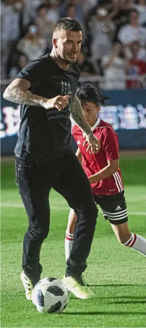  ?? — AFP ?? Just for fun: David Beckham dribbling past a child during a promotiona­l event in China on Wednesday.