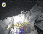  ?? SYRIAN CIVIL DEFENSE WHITE HELMETS / VIA ASSOCIATED PRESS ?? Rescue workers try to remove a boy Monday stuck in the debris of a building in the Qaterji neighborho­od of rebelheld eastern Aleppo, Syria, following an airstrike.