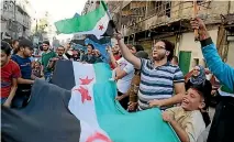  ?? PHOTO: REUTERS ?? People carry Free Syrian Army flags at a protest against evacuating civilians from Aleppo, in the rebel-held al-Shaar neighbourh­ood yesterday.