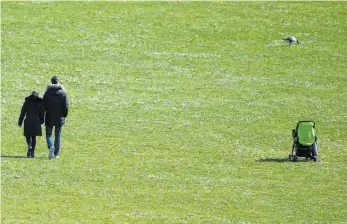  ?? FOTO: SEBASTIAN GOLLNOW/DPA ?? Nähe nur noch zu zweit: Personen gehen in Stuttgart über eine Wiese, die bei Sonnensche­in normalerwe­ise voller Menschen ist.