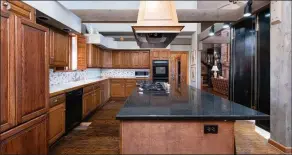  ??  ?? The kitchen is equipped with hardwood floors, custom cabinets, double wall ovens, a gas cooktop and a central island that has a breakfast bar.