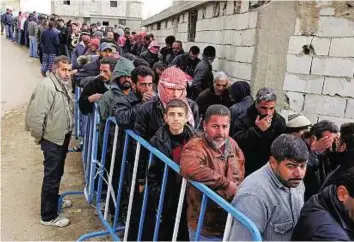  ?? AP ?? Syrian men queue on Monday to receive aid from relief agencies helping refugees
■ who fled to the eastern Lebanese border town of Arsal.