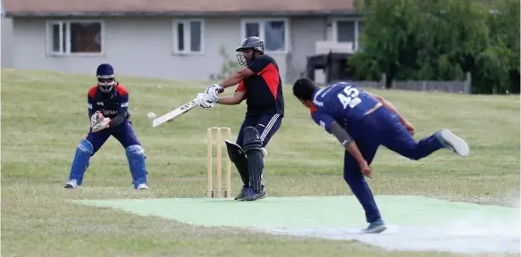  ?? CITIZEN PHOTO BY JAMES DOYLE ?? A Kings XI (black/red trim) striking batsman takes a swing at the ball hurled by a Surrey Cricket Club (blue/red trim) bowler on Sunday afternoon at Vanier Park. The two teams met in the one of the semi-final matches of the Prince George Cricket Club’s third annual cricket tournament.