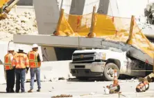  ?? Wilfredo Lee / Associated Press ?? Workers assess the scene Friday in Miami where a pedestrian bridge collapsed the day before, crushing vehicles beneath it.