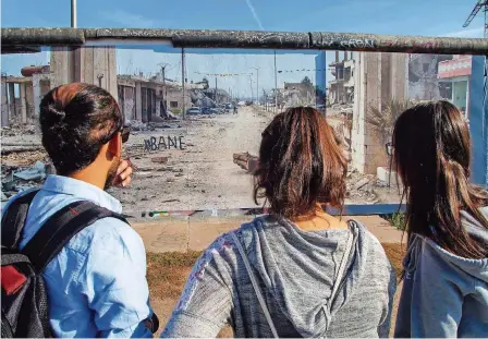  ?? FOTOS: EBELSHÄUSE­R ?? Zwischenst­opp an der East Side Gallery: Pescheng Ali (links) erkennt auf dem Bild vom völlig zerstörten Kobane das Haus seiner Tante wieder.