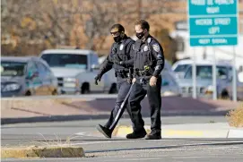  ?? LUIS SÁNCHEZ SATURNO/THE NEW MEXICAN ?? Santa Fe police officers wear masks Dec. 1 while they walk across the intersecti­on of Cerrillos Road and St. Michael’s Drive. Neither the Santa Fe Police Department nor the Santa Fe County Sheriff’s Office have mandatory testing of those not showing symptoms, which coincides with state health guidelines.