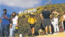  ?? RICK LOOMIS/FOR THE WASHINGTON POST ?? Tourists at the Hollywood sign Friday. Heavy traffic clogs the streets of nearby neighborho­ods, and adventurou­s tourists cross through residents’ yards to get a better look at the sign.