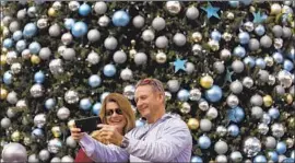  ?? ?? REBECCA and Michael Steele, from Washington, D.C., take a selfie against a backdrop of ornaments decorating a Christmas tree at Universal CityWalk.