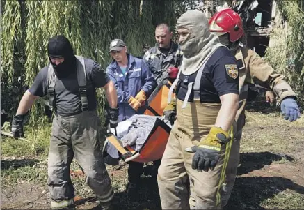  ?? Andrii Marienko Associated Press ?? A UKRAINIAN team transports the body of a woman killed by a Russian missile attack Monday in Chuhuiv, in the Kharkiv region.
