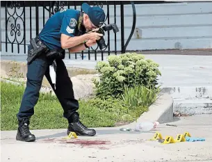  ?? CATHIE COWARD PHOTOS THE HAMILTON SPECTATOR ?? A forensics officer take photos of evidence on the sidewalk out front of 575 Queenston Rd.