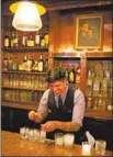  ??  ?? Bartender Joseph Buenrostro prepares drinks at the Kennedy Room in Dallas. A portrait of John F. Kennedy and his wife, Jacqueline, hangs behind the bar.