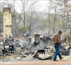  ?? Yin Bogu Sipa USA ?? RALPH COGDILL walks by what remains of his home in Pigeon Forge, Tenn. Fire in the Great Smoky Mountains killed 13 and burned some 1,000 structures.