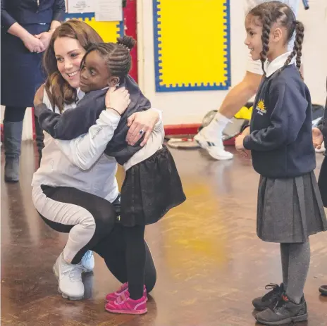  ?? Picture: AFP ?? The Duchess of Cambridge embraces a student at the Bond Primary School in London as others also line up for a hug.