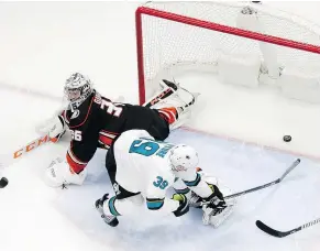  ?? —AP ?? Sharks centre Logan Couture reaches around Ducks goaltender John Gibson to tuck the puck into the net during Game 2 action. The Sharks won 3-2 and lead the series 2-0 heading home.