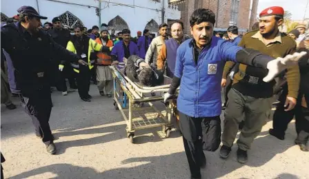  ?? MUHAMMAD SAJJAD AP ?? Workers transport a person wounded Monday when a suicide bomber struck a crowded mosque in the Pakistani city of Peshawar.