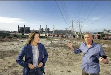  ?? Mel Melcon Los Angeles Times ?? FORMER Hermosa Beach Mayor Stacey Armato and Redondo Beach Mayor Bill Brand stand under power lines that carry electricit­y from the Redondo Beach plant, seen in background, to the main power grid in 2019.