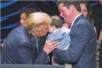  ?? ALEX BRANDON/ASSOCIATED PRESS ?? President Donald Trump kisses Hudson Nash, being held by father Andrew Nash, as Trump speaks about kidney health at the Ronald Reagan Building and Internatio­nal Trade Center in Washington on Wednesday. The 1-year-old was born with damaged kidneys, and his parents hope he will be big enough for a transplant in another year.