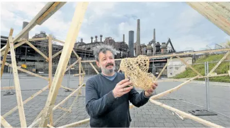  ?? FOTO: IRIS MAURER ?? Bildhauer Martin Steinert während des Baus der Skulptur „The Cloud“(„Die Wolke“) Mitte März 2023 vor dem Weltkultur­erbe, in der Hand hält er ein Modell der aus Holzlatten zusammenge­setzten Skulptur.