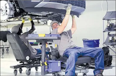  ?? Chattanoog­a Times Free Press/ERIN O. SMITH ?? Employees at Volkswagen’s assembly plant in Chattanoog­a, Tenn., work on a car Thursday. Industrial output fell last month, the Federal Reserve said Friday.