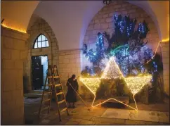  ?? (AP/Oded Balilty) ?? A nun cleans the floor Dec. 12 after decorating the entrance to a church with Christmas lights in Jerusalem’s Old City.