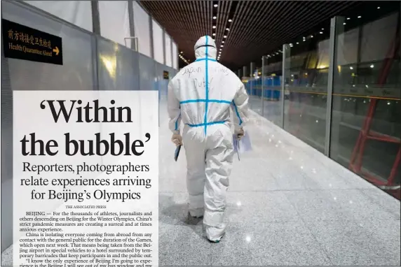  ?? (AP/Jae C. Hong) ?? A member of airport personnel dressed in protective gear leads passengers into the customs area Monday at the Beijing Capital Internatio­nal Airport ahead of the 2022 Winter Olympics in Beijing.