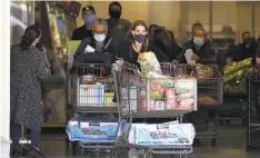  ?? Marcio Jose Sanchez / Associated Press ?? Shoppers exit at Costco in Santa Clarita on Friday on the brink of a new stayathome order that would curtail or close businesses.