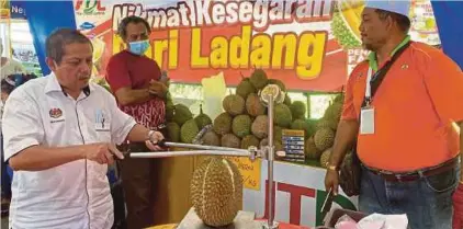  ?? (Foto Nur Izzati Mohamad/bh) ?? Muhamad Mustahapa (kiri) di gerai jualan durian pada program FAMA Fest di Seberang Jaya, Butterwort­h, semalam.
