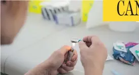  ?? NICK KOZAK FOR POSTMEDIA NEWS ?? A drug user prepares heroin for injection in Moss Park in Toronto, at one of the temporary safe injection sites that have popped up during the wait for permanent ones.