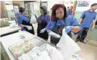  ?? DE SISTI / MILWAUKEE JOURNAL SENTINEL MIKE ?? Ebony White packs up a meal to be handed out at Barbee Montessori School on North Teutonia Avenue.