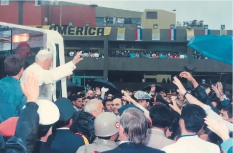  ??  ?? Ya en el papamóvil, alza la mano para correspond­er el saludo del pueblo que acudió al aeropuerto para recibir al Mensajero del Amor.