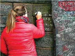  ?? AFP ?? Visitors write on the wall alongside the gates to Strawberry Field.