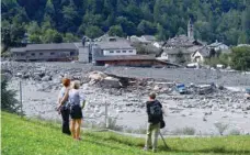  ?? — Reuters ?? People look at the damage caused by a landslide in the village of Bondo in Switzerlan­d on Saturday.