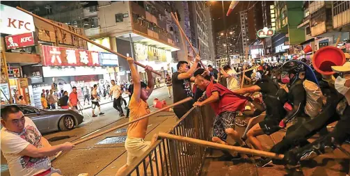  ?? AP ?? BEDA KUBU: Sekelompok massa menyerang demonstran dengan tongkat Senin malam (5/8). Mogok masal dan aksi di berbagai titik membuat transporta­si di Hongkong hampir lumpuh.