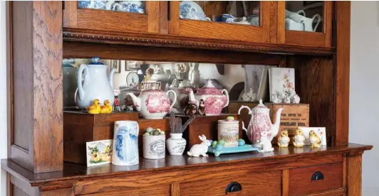  ?? ?? Mirrors on the interiors of hutches serve in a multitude of ways. A mirror as the backdrop in Debbie’s dining room hutch reflects sunlight through the room, brightens the interior of the cabinet and allows visibility of an English teapot collection from all angles. Consider propping up a framed mirror in the back of a cabinet’s recessed area for a boost of illuminati­on.